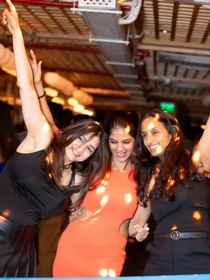 Hands in the air for the classics. Three friends dancing together, fully immersed in the high-energy vibe of the party.