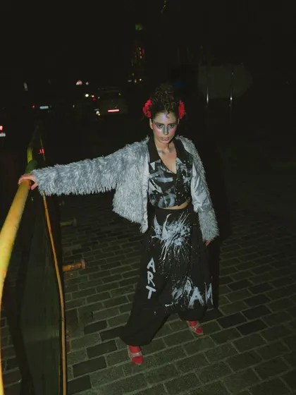 This wide shot from 'Lampione' captures the full outfit and the dark, atmospheric mood of the city street at night.