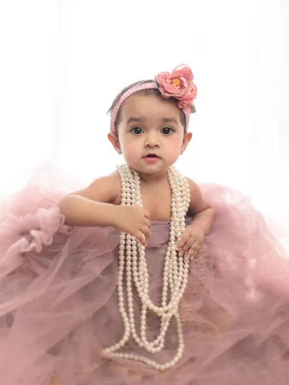 A sweet baby girl in a dusty pink tulle dress, adorned with pearls. This sitter session portrait has a timeless, painterly quality that makes it a beautiful piece of art.