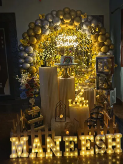 A full view of the gold and silver themed second birthday party, complete with a picket fence and marquee letters.