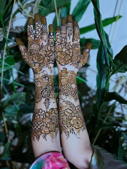 A full view of the floral design against a lush green backdrop. The natural light highlights the details of the henna.