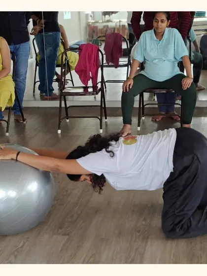 An expectant mother uses a stability ball for a gentle forward bend, a pose that helps to release tension in the lower back and create space in the pelvis.