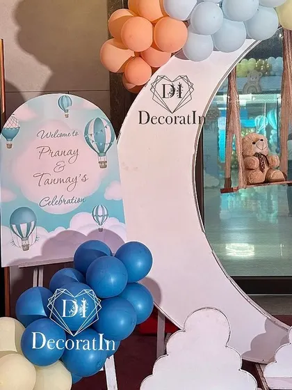 A welcome area featuring a moon-shaped prop with a teddy bear on a swing, and a personalized easel sign.