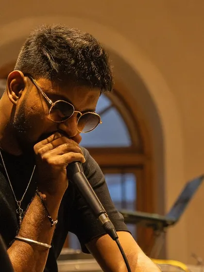 I bring the beatbox mic close during Monsoon Jam at Sabha Bengaluru, with the room's warm lighting behind me.