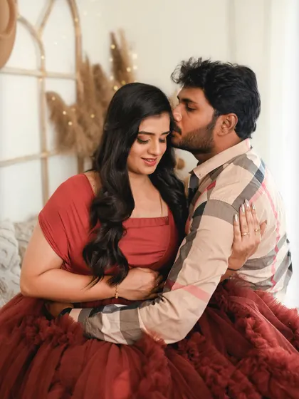 A tender kiss on the cheek. This cozy studio shot is filled with warmth and affection, perfectly capturing the love between the parents to be.