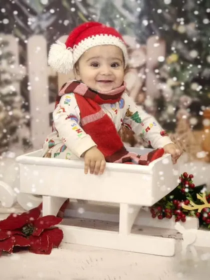 Jingle bells, jingle bells. This little one is enjoying a ride in Santa's sleigh during a fun and festive Christmas-themed sitter session.