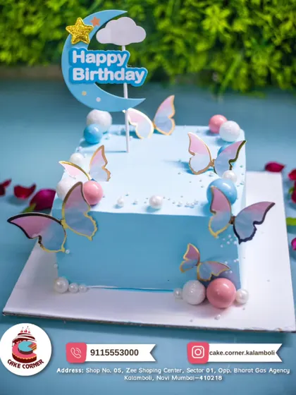 A dreamy light blue square cake decorated with pastel butterflies and pearls. The moon and star topper adds a touch of nighttime magic.