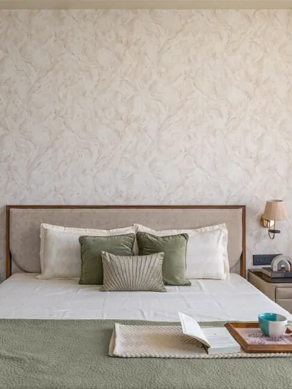 A frontal view of the custom bed with its faux leather headboard and matching side tables. The simple, clean design is complemented by the textured wallpaper and elegant wall sconces, creating a balanced and restful space.