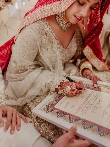 The bride signs her Nikah contract, her expression serene and focused.