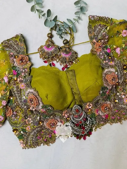 A flat lay of the mustard raw silk blouse, showing the intricate hand embroidery and 3D floral details.