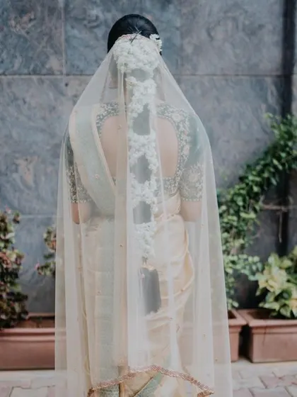 A view from the back, showing the bride's intricate hairstyle and the sheer veil over her embroidered blouse.