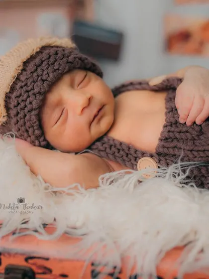 A slightly different angle showing the baby's tiny hand and the button details on his knitted outfit. Every small element is carefully considered to create a beautiful final image.