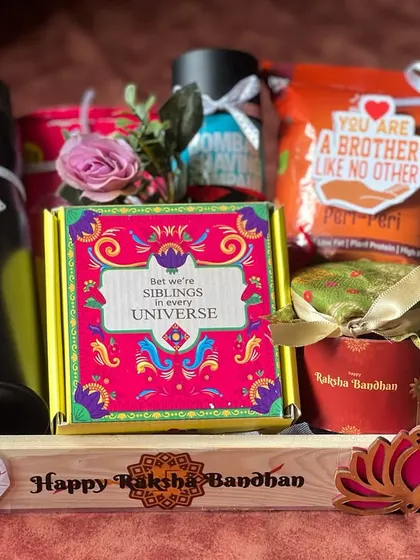A vibrant Rakhi hamper for a brother, featuring a personalized sipper, snacks, and a colorful box, all in a wooden tray.