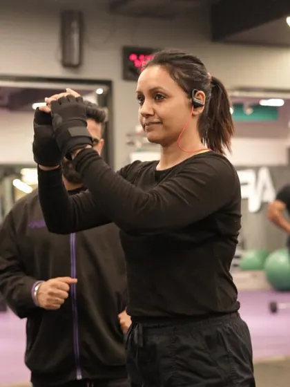 A client focuses on her workout, with her trainer nearby to offer support and motivation. This partnership is key to achieving fitness goals.