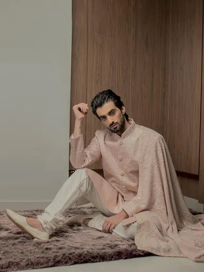 The artistry of our rose gold sherwani is evident in this shot, which captures the flow of the embroidered stole and the detailed threadwork on the cuffs and collar.