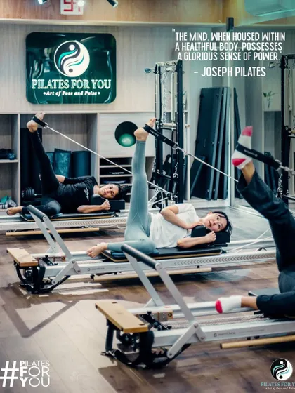 A beautiful shot of clients performing a leg series on the Reformer, showcasing the synchronized and graceful movements that Pilates develops.