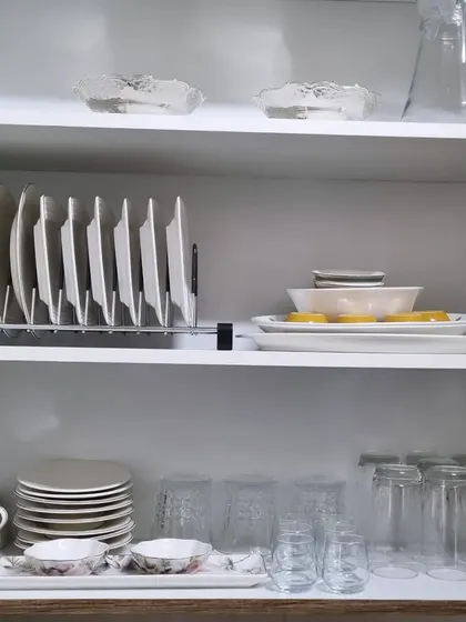 An organized crockery cabinet with daily-use plates stored vertically in a rack for easy access. This is a simple trick to make setting the table quicker.