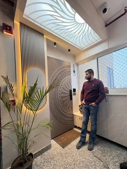 Here I am at a completed project in Nirala Estate, standing by the grand entrance. The design features an intricately carved main door, a CNC-cut ceiling panel, and stylish wall paneling.