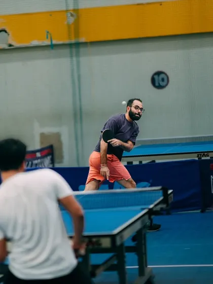 Two colleagues compete in a friendly but focused game of table tennis. Offering a variety of sports ensures that employees who are not badminton players can still actively participate and enjoy the event.