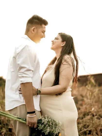 A classic romantic portrait of the couple looking into each other's eyes, surrounded by the warm tones of a field at sunset.