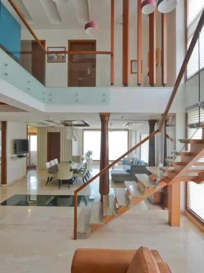 From the drawing room of the Sobti Residence, the view opens up to the dining and family lounge. The double-height volume and open-plan layout create seamless visual connectivity, enhanced by the modern floating staircase.