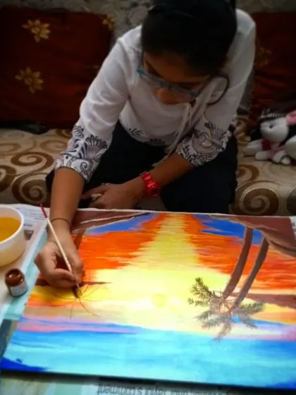 One of my students is deeply focused on her acrylic painting of a sunset. In my classes, I encourage this level of concentration, which helps children develop patience and attention to detail.