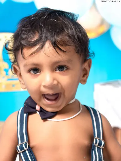 A little prince celebrating his first birthday with a royal blue cake smash. The setup includes a crown, balloons, and a delicious-looking cake ready to be smashed.