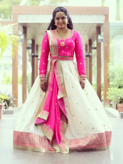 Deepika looks stunning in this custom-designed half saree. I paired a simple, elegant off-white skirt with a vibrant pink long-sleeved blouse and a matching draped dupatta.