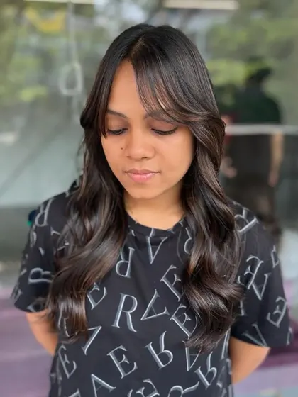 A portrait of the client, her hair styled with face-framing bangs and soft waves.