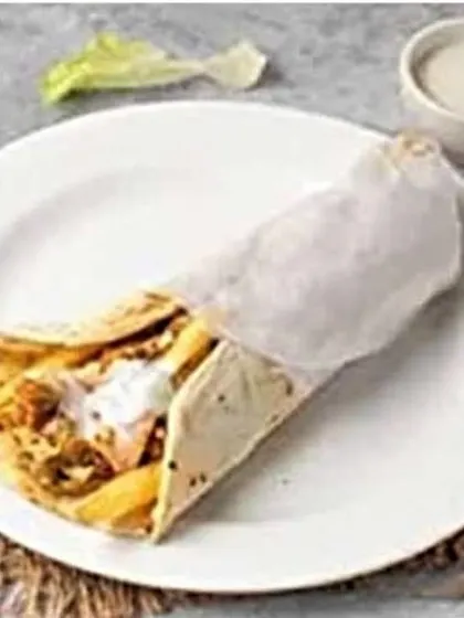 A slightly different angle of the Mexican-style roll, showing the creamy sauce drizzled over the chicken, jalapeños, and fries before it's fully wrapped.