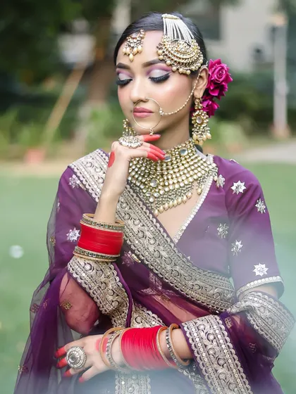A regal bridal look in a deep purple lehenga. The makeup features a soft smokey eye and perfectly defined brows.
