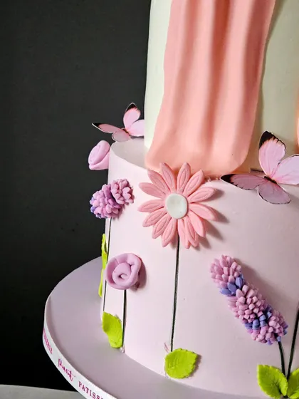 A close-up of the bottom tier of the two-tiered bow cake, showing the intricate, individually piped lavender flowers.