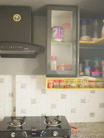 A view of an L-shaped kitchen with a playful touch of yellow inside the open shelving. This project for a 3BHK apartment showcases our ability to incorporate pops of color into a neutral design scheme.