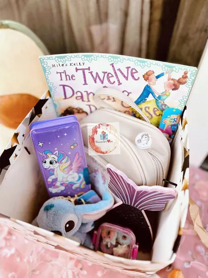 A unicorn-themed gift box for a young reader. It includes "The Twelve Dancing Princesses" book, a unicorn-themed water bottle, a Stitch plush toy, and a mermaid tail coin purse.