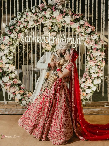 A romantic portrait of the couple under a neon sign with their wedding hashtag, "sabkuchmilgaya".