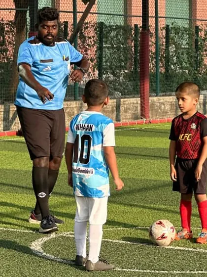 A coach guides a player during a Blue Cubs league game. We provide constant support and instruction on the field.