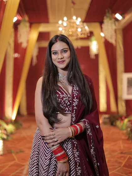 A full set of photos of a client looking stunning in our wine-colored chevron lehenga at a wedding reception.