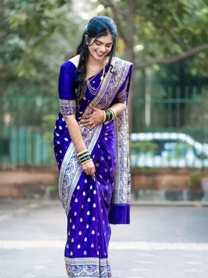 A full-length shot of the bride, showing the beautiful drape and intricate silver zari work on her royal blue Paithani saree.