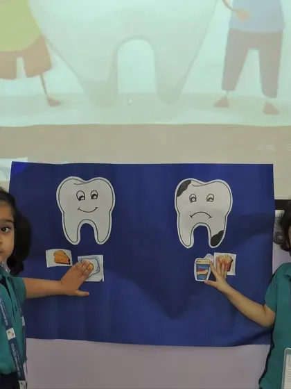 Two students demonstrate the difference between healthy and unhealthy teeth. We use visual aids to teach important lessons about oral hygiene and making good food choices.