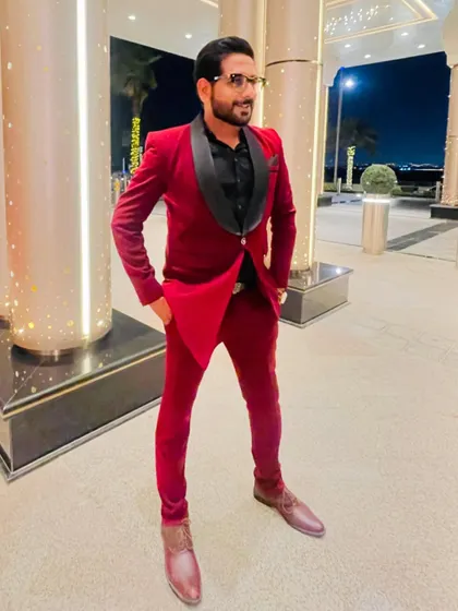 A stylish pose in a velvet red tuxedo before hosting a grand reception in Dubai. My presentation is a key part of the premium hosting service I provide.