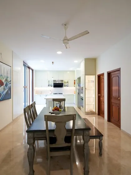 An open-plan dining area that flows into the kitchen, featuring a rustic wooden table and bench that adds warmth and charm to the modern space.