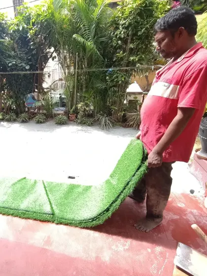 A team member carefully positions a large section of artificial grass. I take great care to align the pieces for invisible seams.