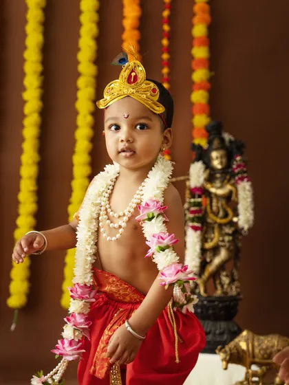 A handsome little Krishna standing proudly in his festive attire.