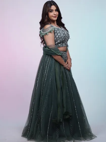 A full-length shot of the dark green lehenga. The combination of the sequined skirt and the feather-detailed blouse is pure elegance.