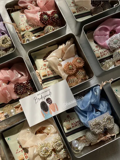 A different angle of our best-selling bridesmaid favor tins. The variety in colors for the scrunchies and earrings shows how we can customize these gifts for each individual bridesmaid.
