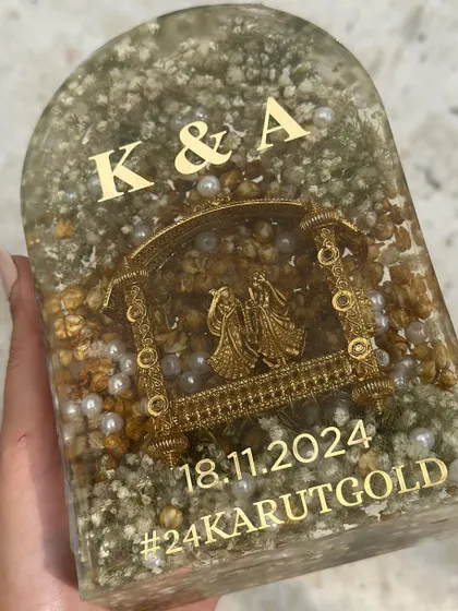 Another look at the custom arch-shaped keepsake, preserving both varmala flowers and kaleera elements. The gold detailing of the Radha-Krishna jhula adds a divine touch to this wedding memory piece.