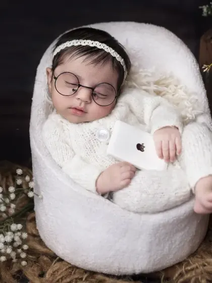 The littlest tech genius, dreaming of future innovations. This creative newborn portrait with glasses and a mini iPhone adds a touch of modern humor to your baby's first photos.