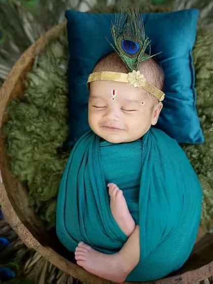For my littlest clients, I offer unique traditional themes like this adorable Kaanha setup. This newborn photoshoot features a peacock feather headpiece and a serene, sleepy pose.