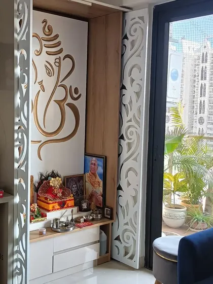 A beautiful pooja corner with intricate white jaali doors featuring a Ganesha cutout. This unit is designed to be a peaceful and spiritual focal point in the home, with a view of the balcony garden.