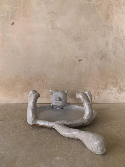 A side view of the cat-shaped dish, showing its long, elegant tail.